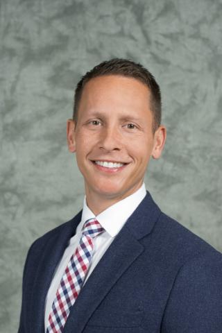 Headshot of Glenn Sterner with short brown hair, white shirt, red, white, and blue tie, and blue jacket.