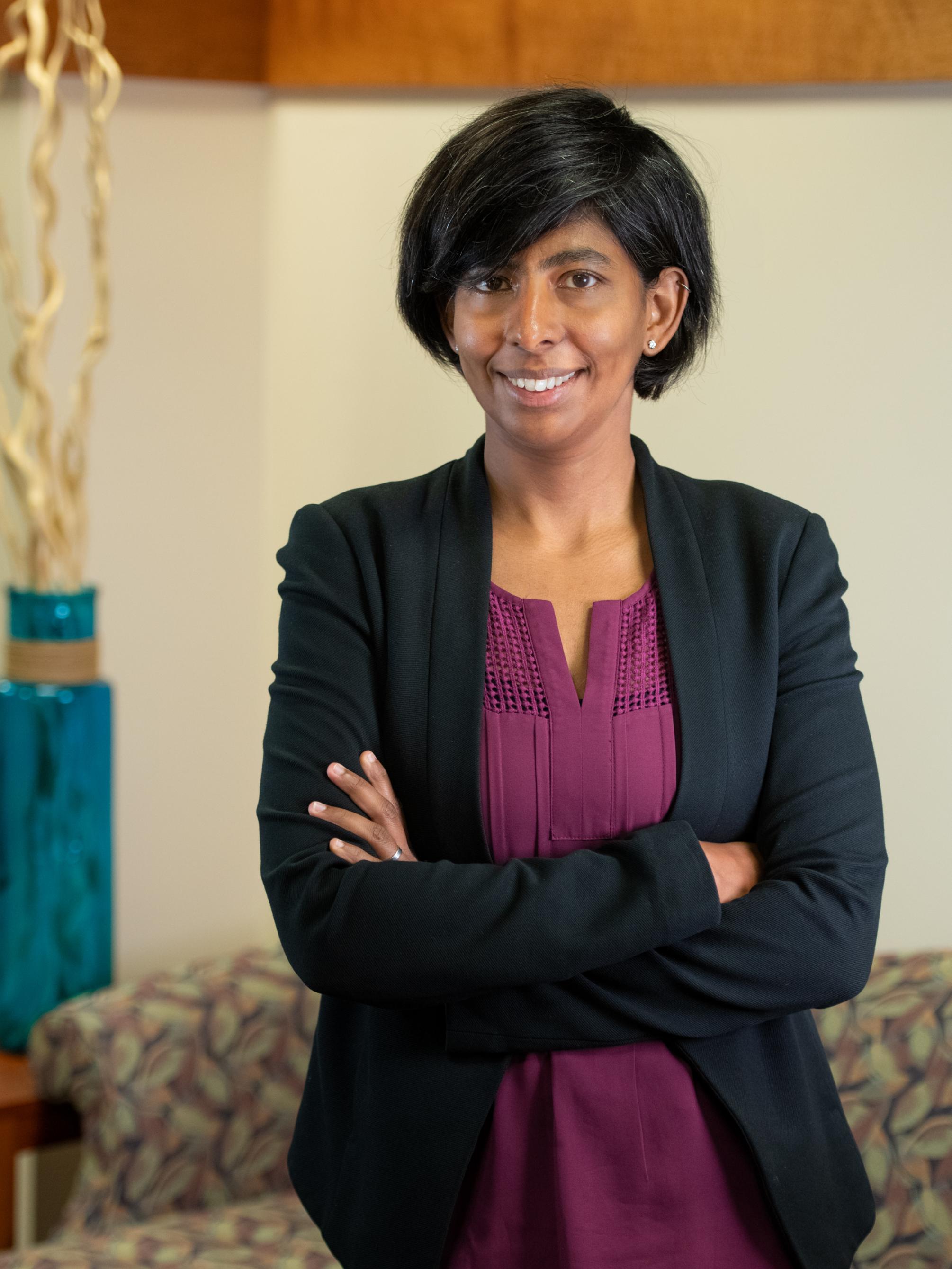 Maithreyi Gopalan head shot with black sweater and maroon shirt and short black hair.