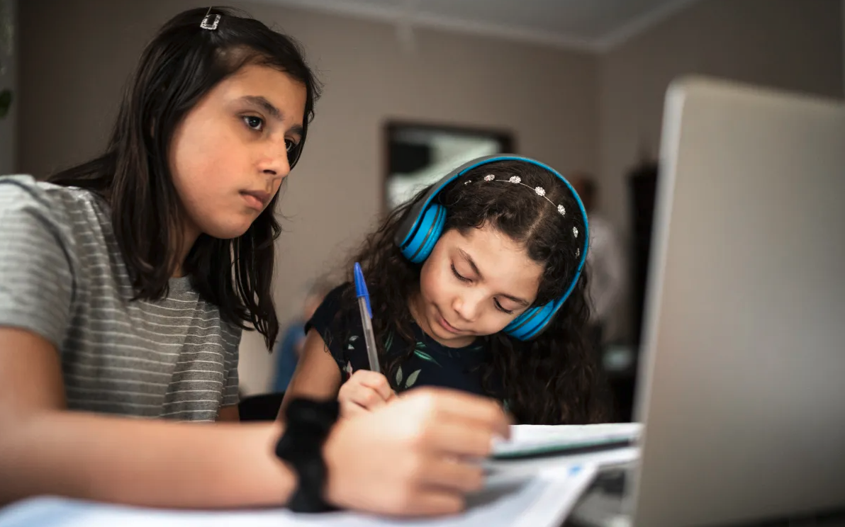 Latino siblings studying from in front of computer