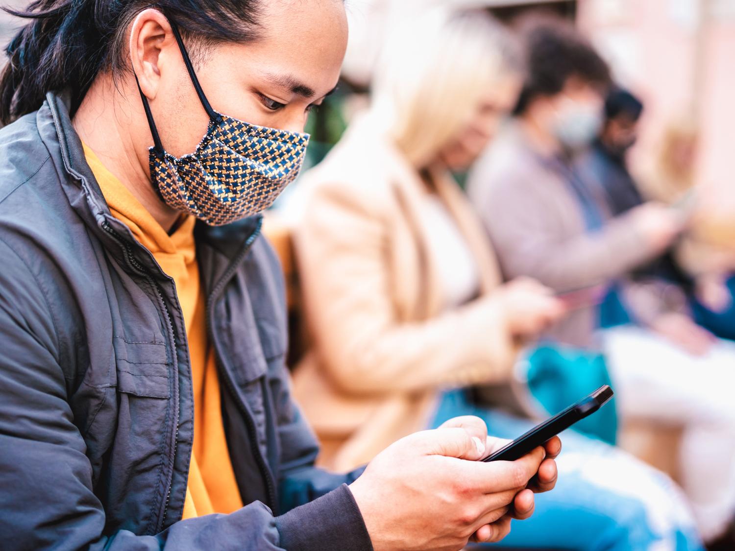 People wearing masks using smart phones.