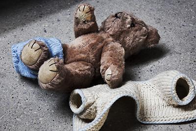 Photo of a teddy bear with its discarded sweater next to it.