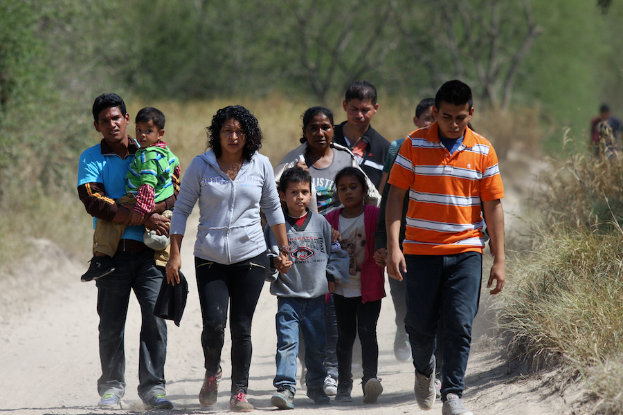 Immigrant children walking on a dirt road.