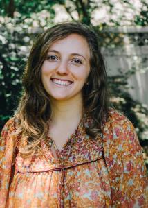 Caucasian woman with long brown hair, brown eyes, friendly smile, wearing a nice floral blouse