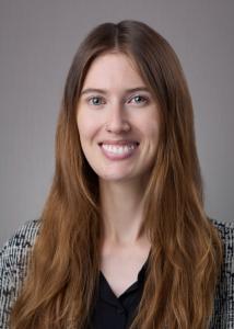 Caucasian woman with long blonde straight hair, hazel eyes, friendly smile, wearing a black bouse and a stylish boucle jacket