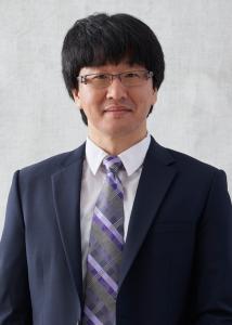 Headshot of Hyun Woo Kim with short dark brown hair and blue suit.