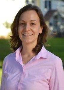 Headshot of Kathleen Sexsmith outsidewith long brown hair wearing a pink collared shirt. 