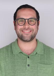 Caucasian man with short brown hair, hazel eyes, friendly smile, clean shaven, wearing a sage green polo and glasses