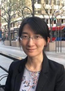 Asian woman with short black hair, brown eyes, friendly smile, wearing glasses, black jacket and floral blouse