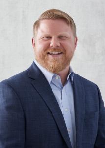 Headshot of Michael Donovan, short red hair and beard, blue suit