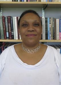 Headshot of Niki Dickerson Vonlockette in front of a book shelf wearing a white shirt and necklace. 