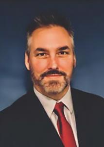 Headshot of Steven Branstetter with dark grey hair wearing a red tie and black jacket.
