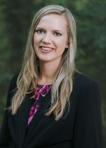 Headshot of Taylor Scott with long blonde hair, black blazer, and floral blouse.