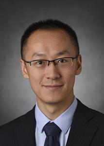 Headshot of Qiushi Chen, an Asian man with short hair and glasses wearing a black suit jacket, dark colored tie, and light colored shirt.