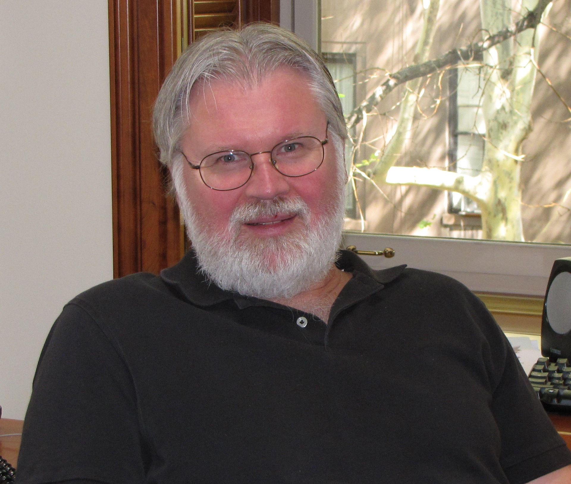 Photo of Douglas Massey with grey hair, beard, glasses, and black shirt.