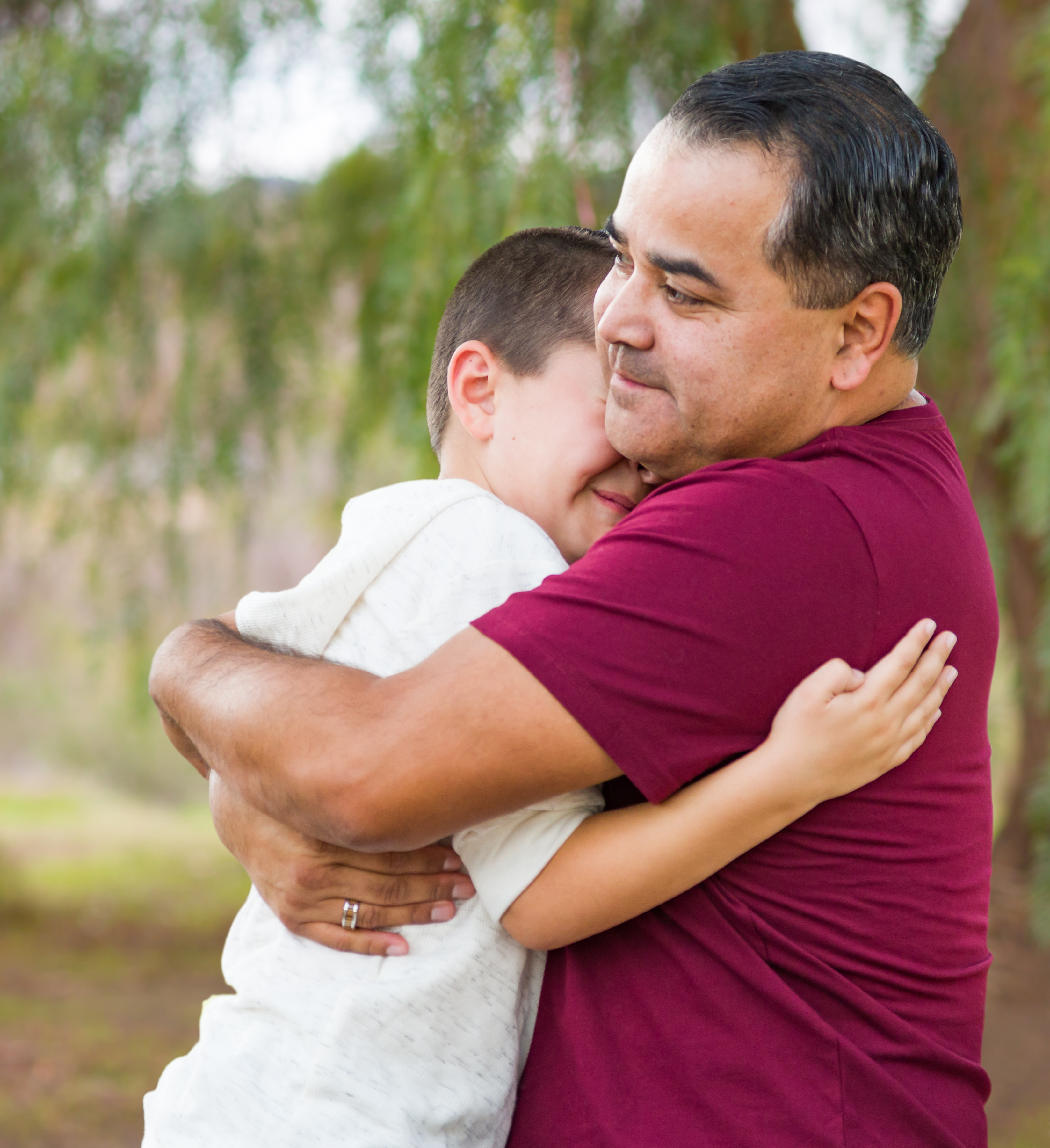 A hispanic father embracing his son.