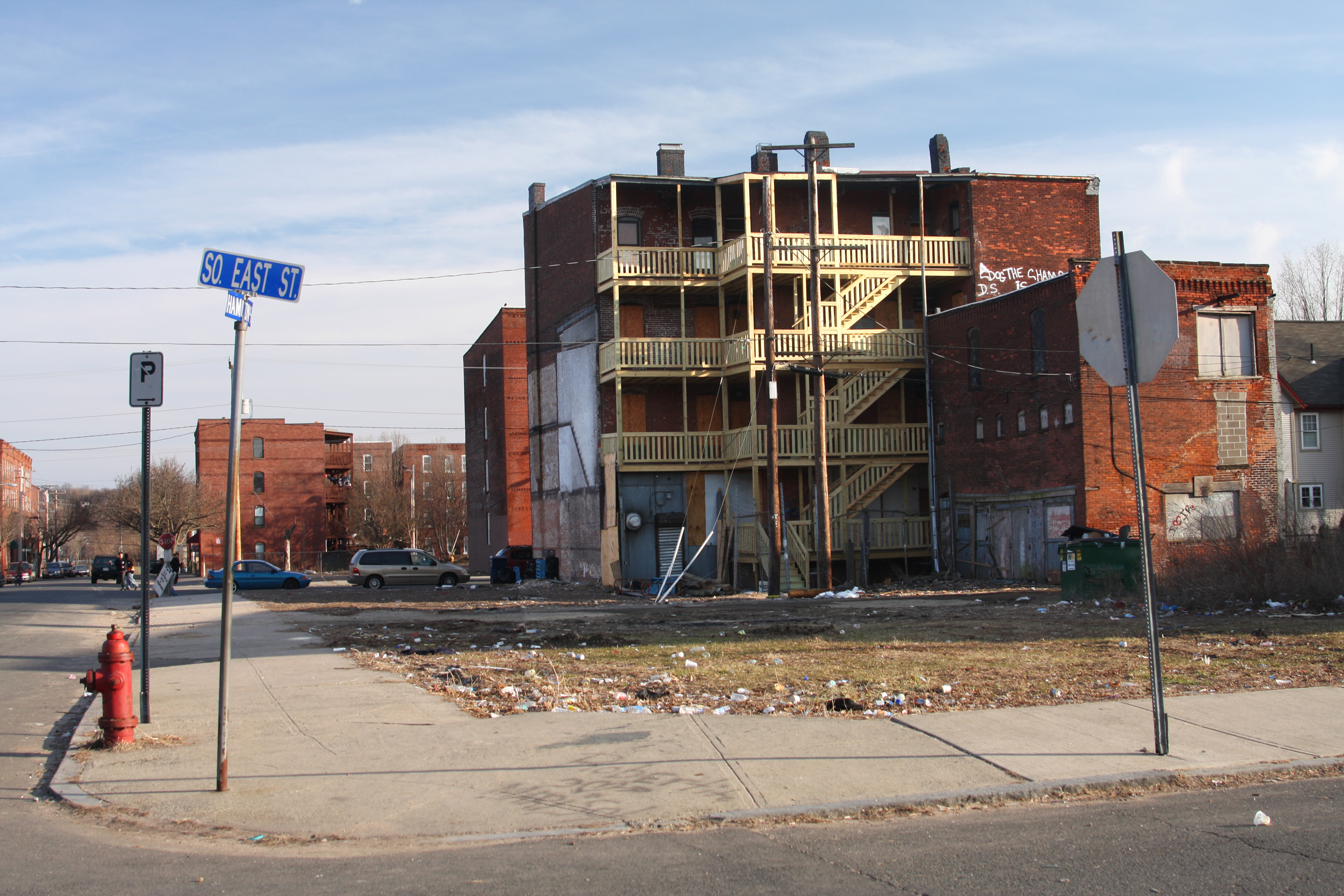 Photo of a ghetto with a rundown building on a corner, graffiti, and trash.