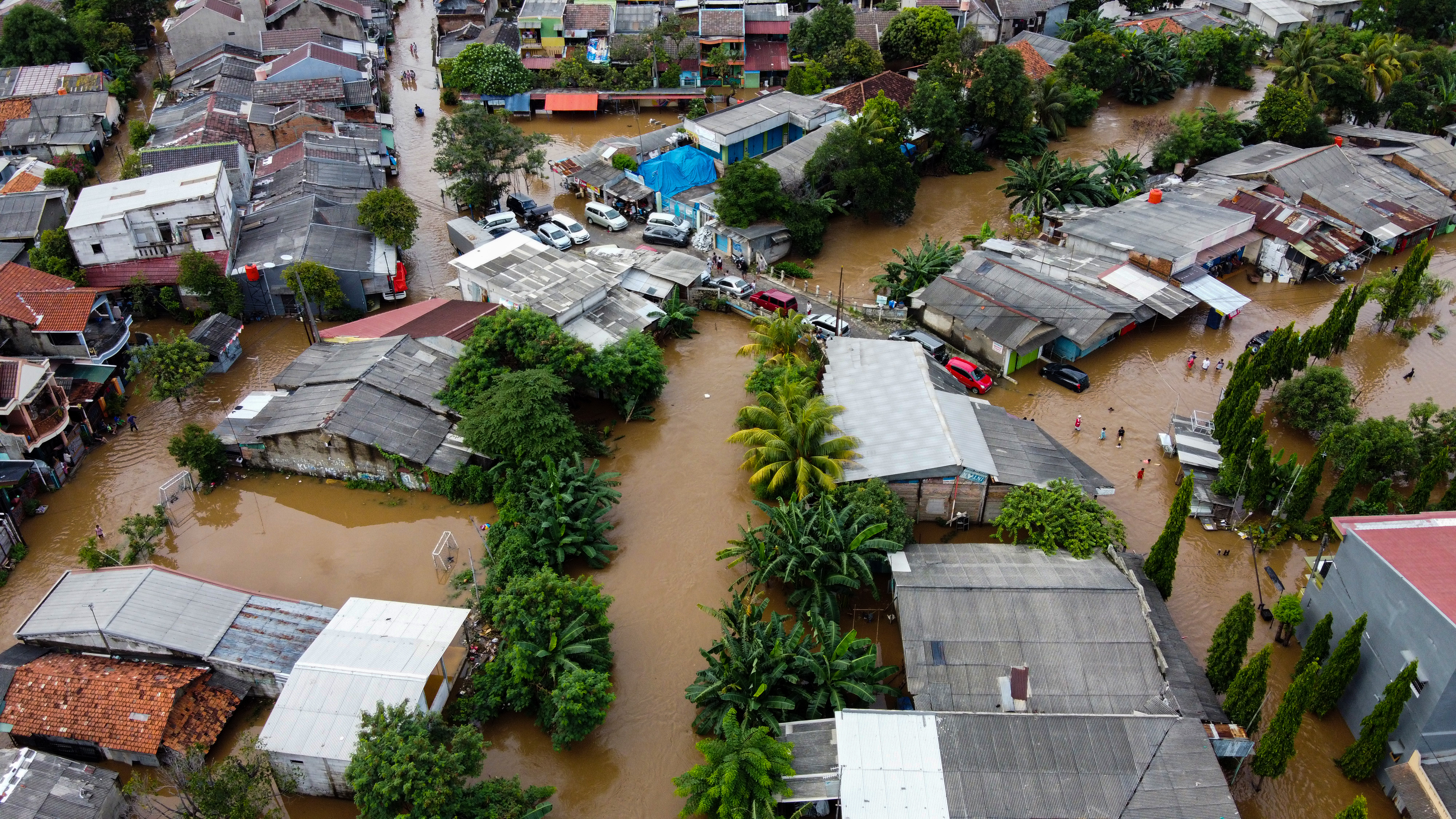 Aerial view of houses surrounded by muddy flood water.