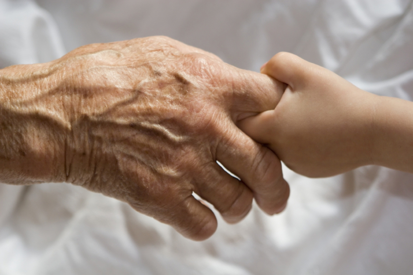 Elderly person's hand reaches out to a child's hand