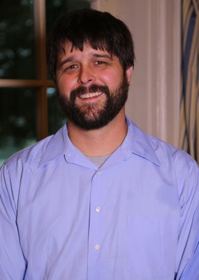 Headshot of David with dark brown hair, beard, and blue shirt.