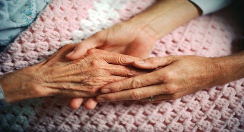 Photo of two younger hands holding an older hand.
