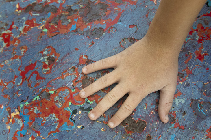 Photo of a child's hand placed on a multi-colored floor.