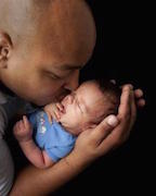 Photo of African-American father cradling his infant son.