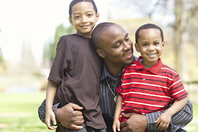 Two african-american children hugged by father.
