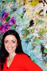 Headshot of Frances Blanchette with black hair and a red blouse standing in front of a multi-colored painting.