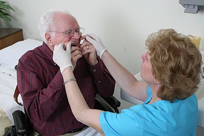 Photo of a dental hygienist and an older male patient.