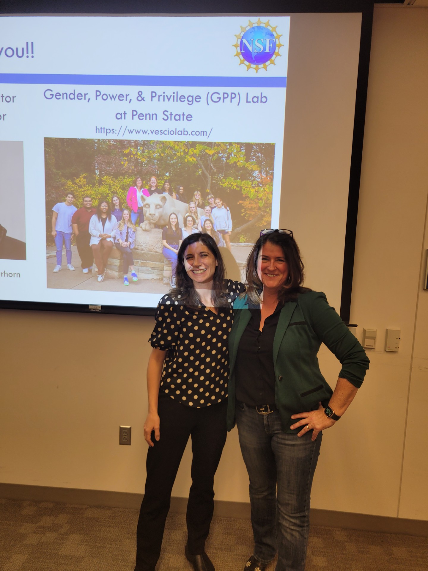 Photo of two women standing in front of a PowerPoint presentation.