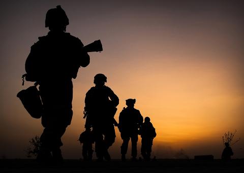 Shadow outlines of four marines against a sunset.