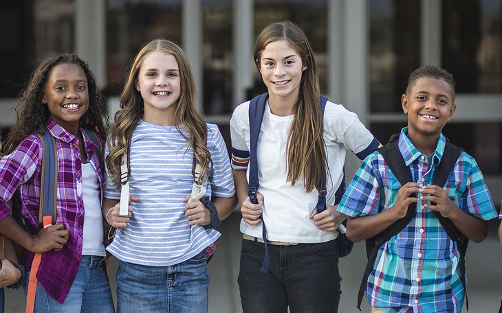 Four middle school-aged kids wearing backpacks.