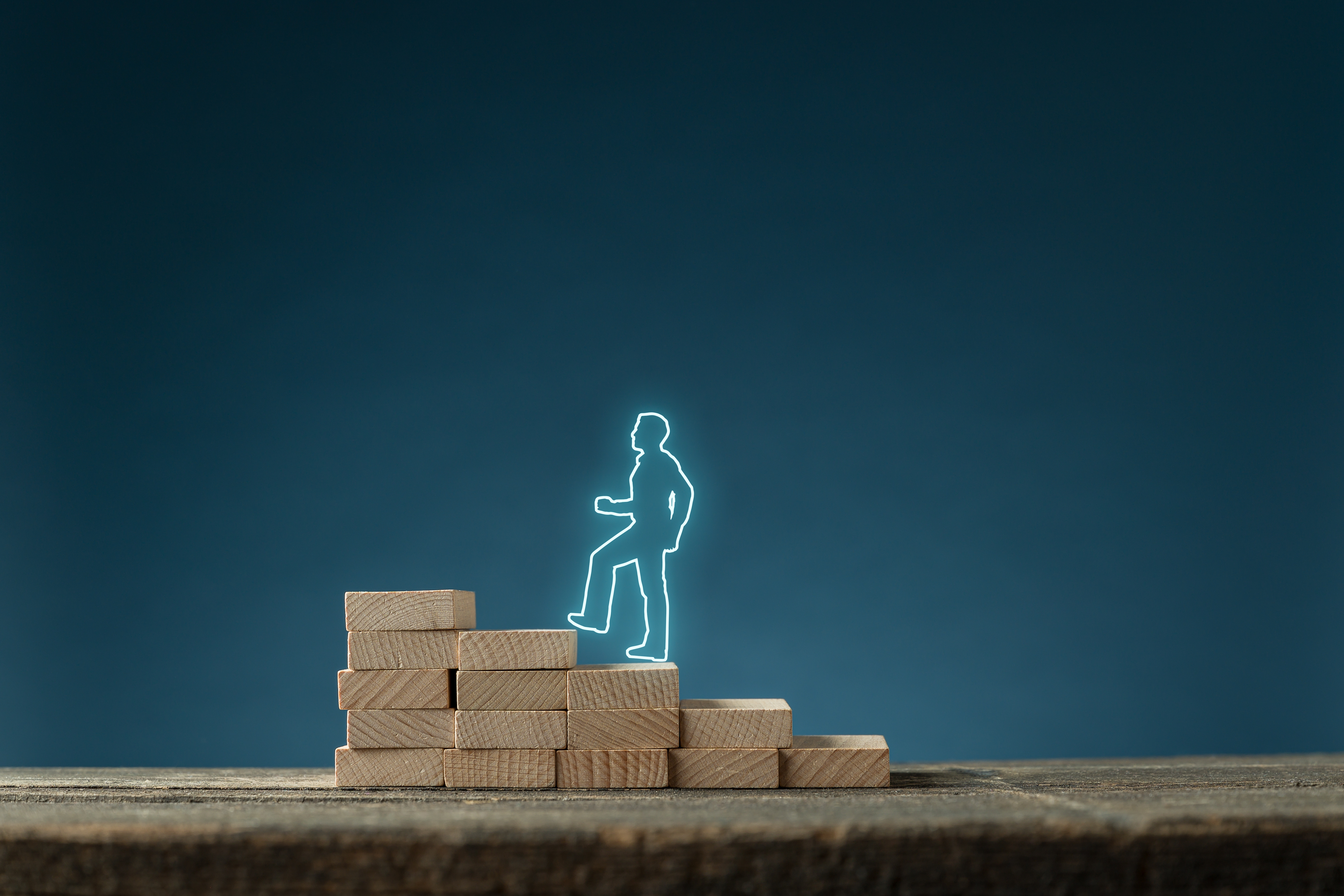 Light blue figure of a person climbing up a set of blocks.