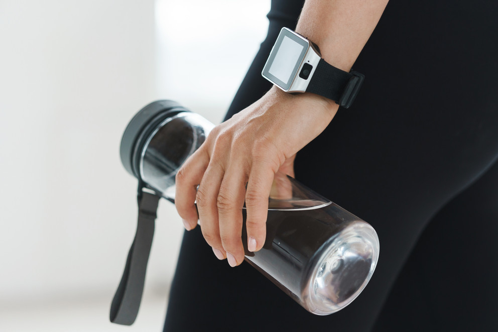 Woman holding water bottle with smart watch.