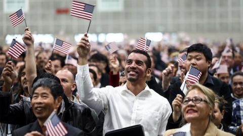 A gathering of immigrants waving small American flags.