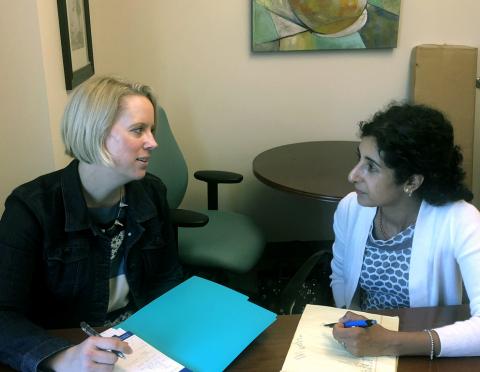 Dr. Jennifer Kraschnewski and Dr. Deepa Sekhar sitting together at a table and going over notes.