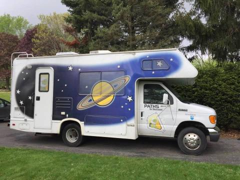 Photo of the white RV with a mural of the night sky painted on the side.