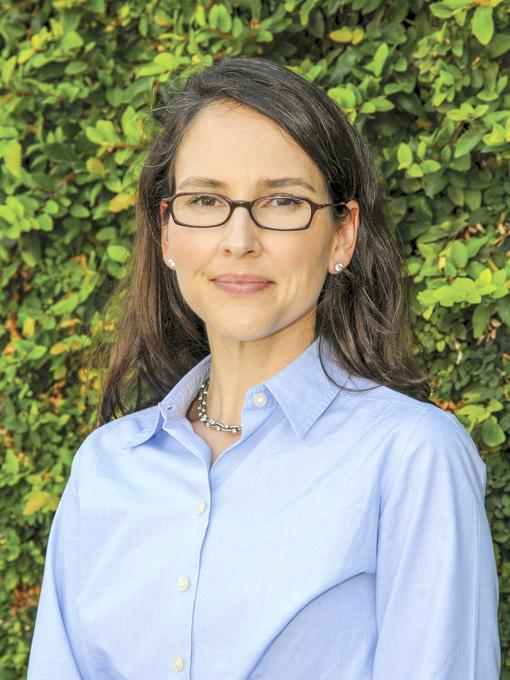 Francesca Lopez head shot in blue button down shirt, long dark brown hair and brown-framed glasses in front of green tree.