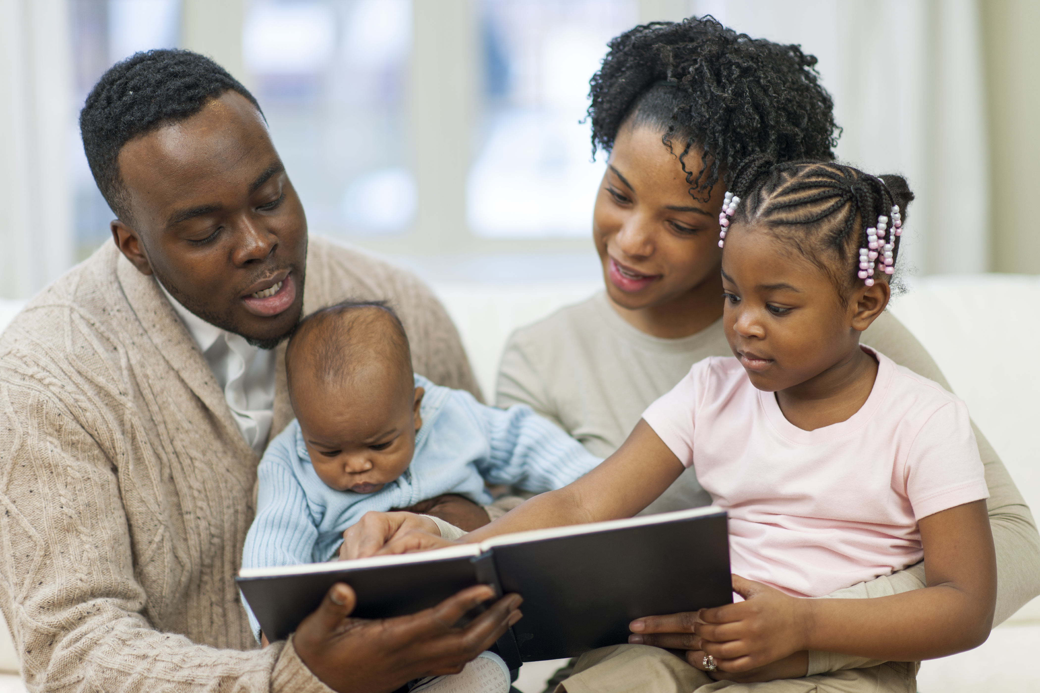 African American family reading to their young children.