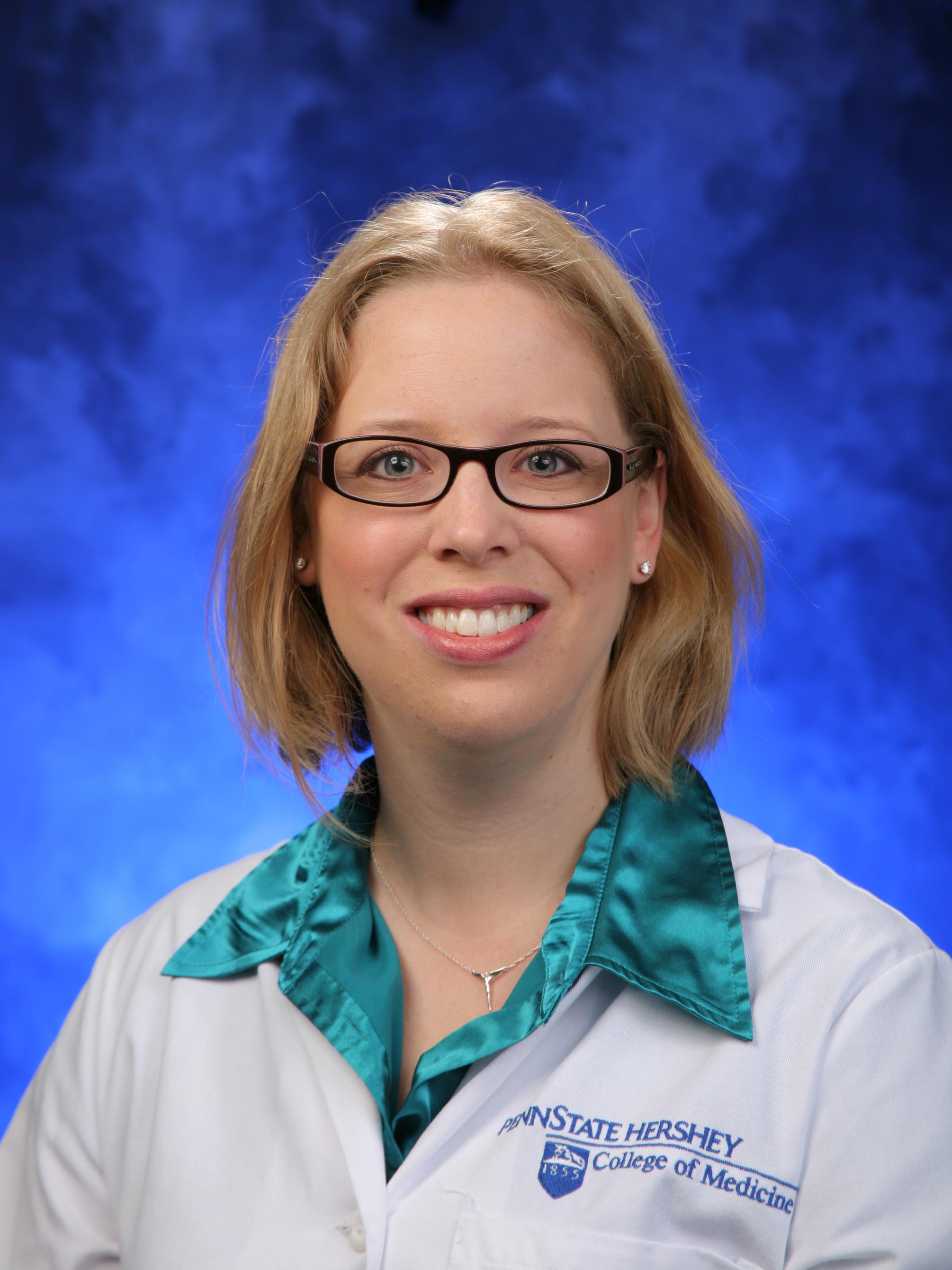 Jennifer Kraschnewski headshot with short blonde hair, glasses, green shirt and white Penn State College of Medicine lab coat