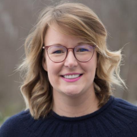 Headshot of Nikki Crowley with blonde hair, glasses, and navy blue sweater.