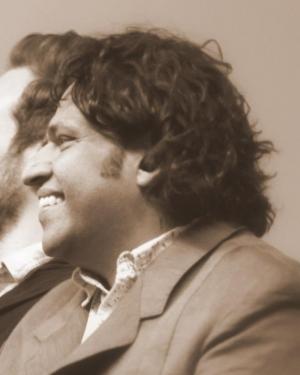 Black and white headshot of Nilam Ram with dark hair, gray jacket, and light colored shirt.