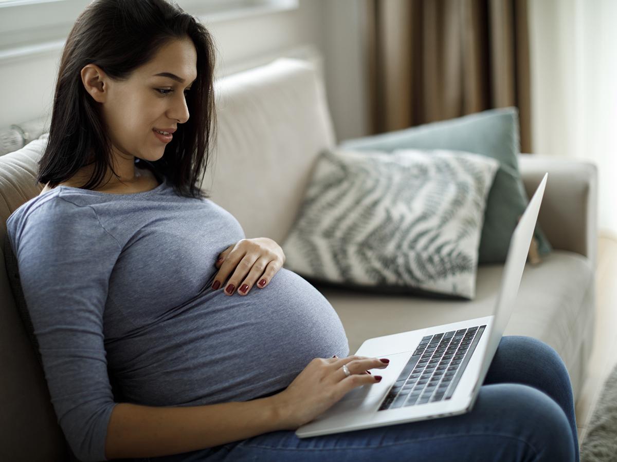 Pregnant woman sitting down with a laptop computer