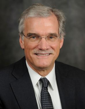 Headshot of Robert Groves with gray hair, glasses, mustache, white shirt, patterned tie, and black jacket.