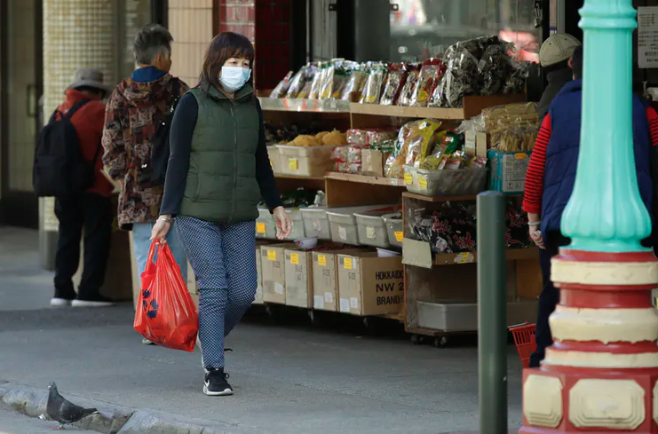 A masked shopper walks in the Chinatown district of San Francisco.