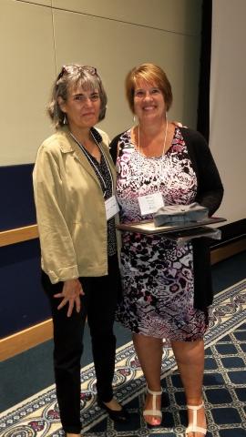 Photo of Sherry Yocum holding her award and standing next to Susan McHale.