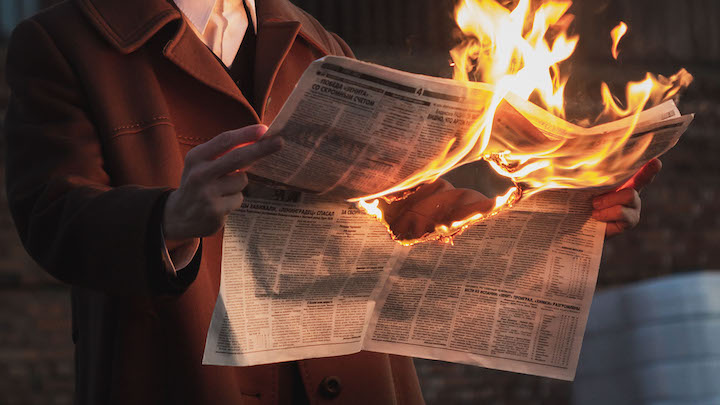 Man holding burning newspaper