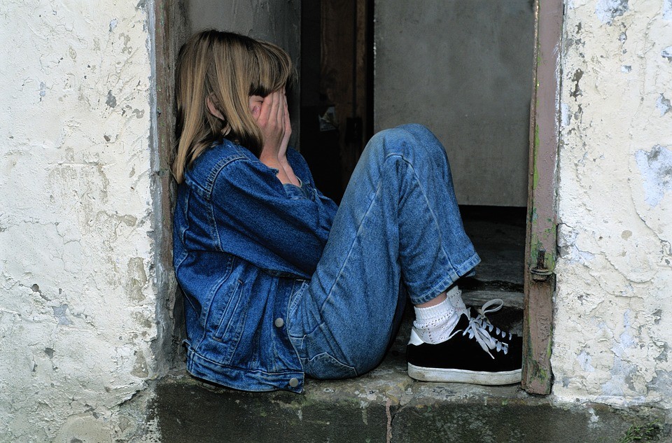 Young girl sitting on the ground crying.