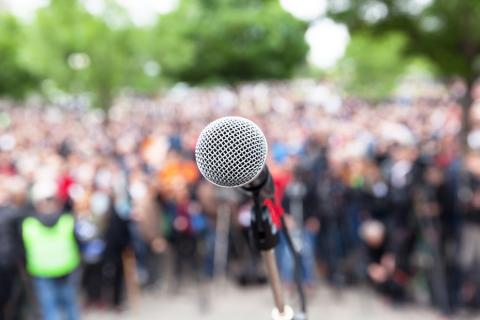 Photo of a microphone in front of a large crowd.