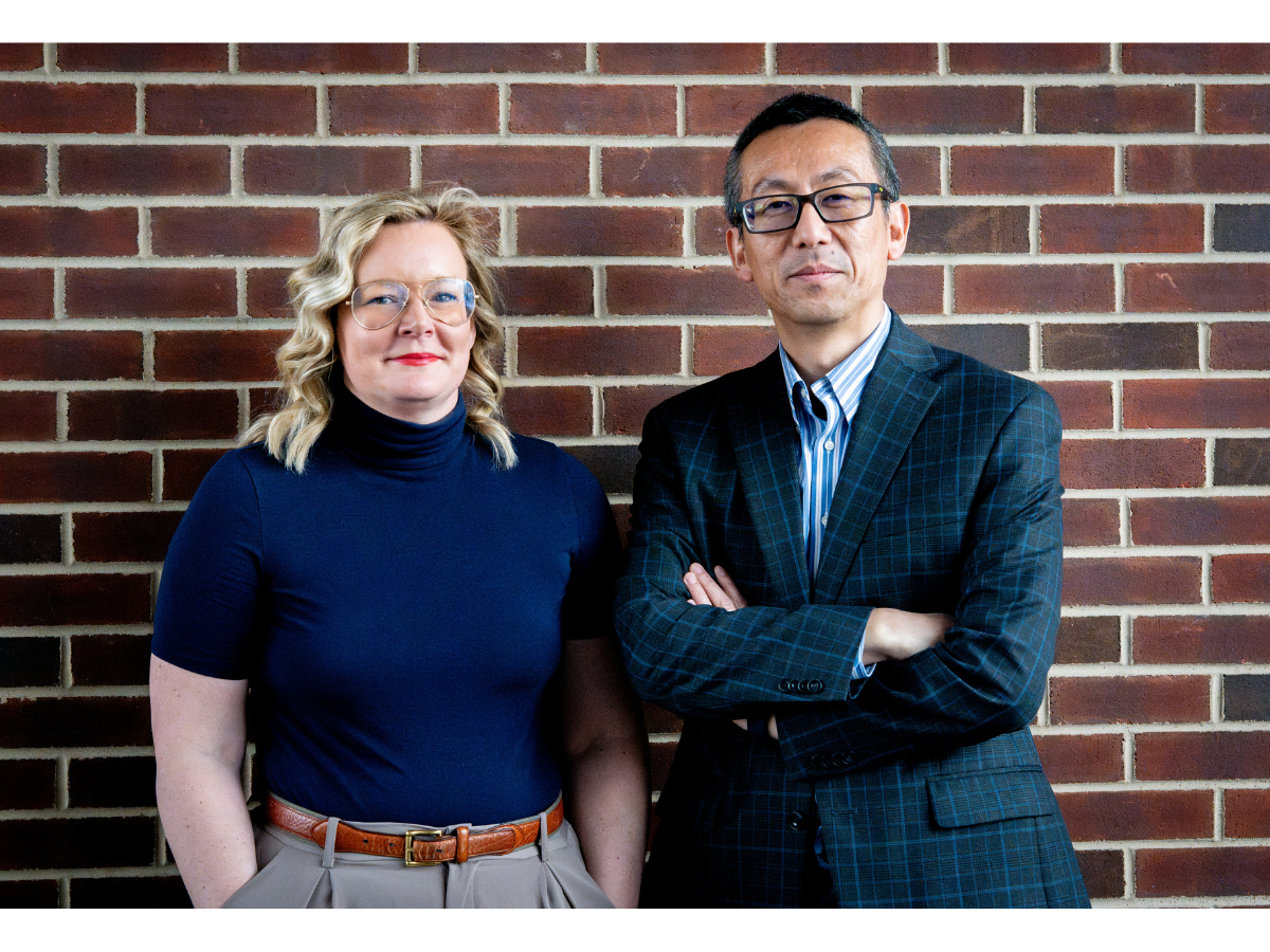Photo of Nikki Crowley, principal investigator, with blonde hair, glasses, navy blouse, and red lipstick and collaborator Nanyin Zhang with black hair, glasses, plaid suit jacket, and blue and white striped shirt.